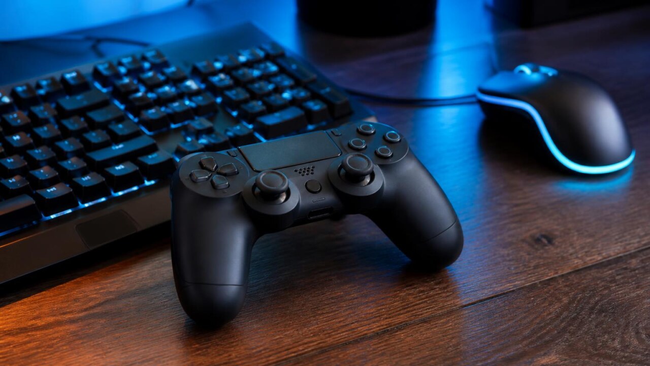 Controle de videogame ao lado de teclado e mouse, sugerindo dúvida sobre versão para PC