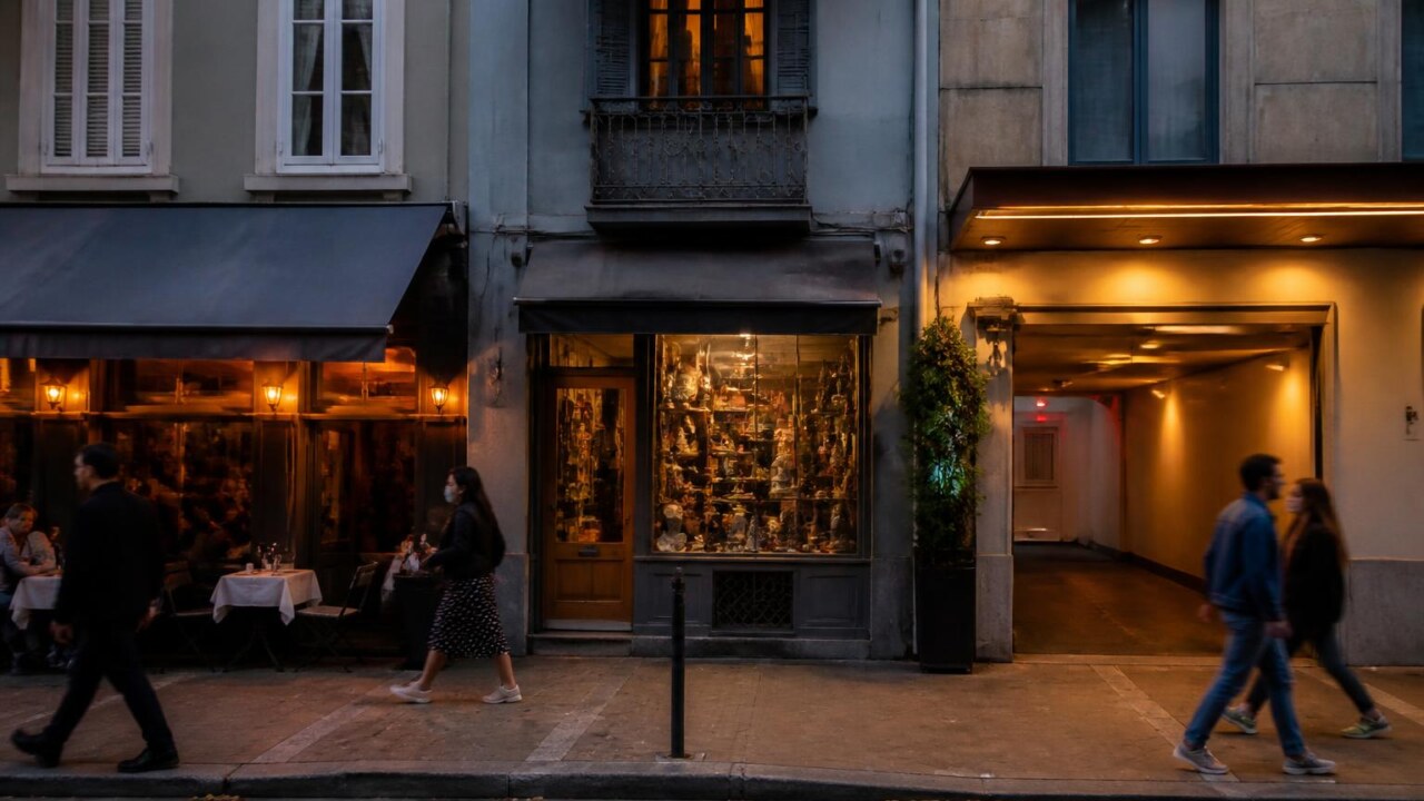 Fachada de rua com restaurante, loja e motel ao entardecer representando a vida urbana e memória local.