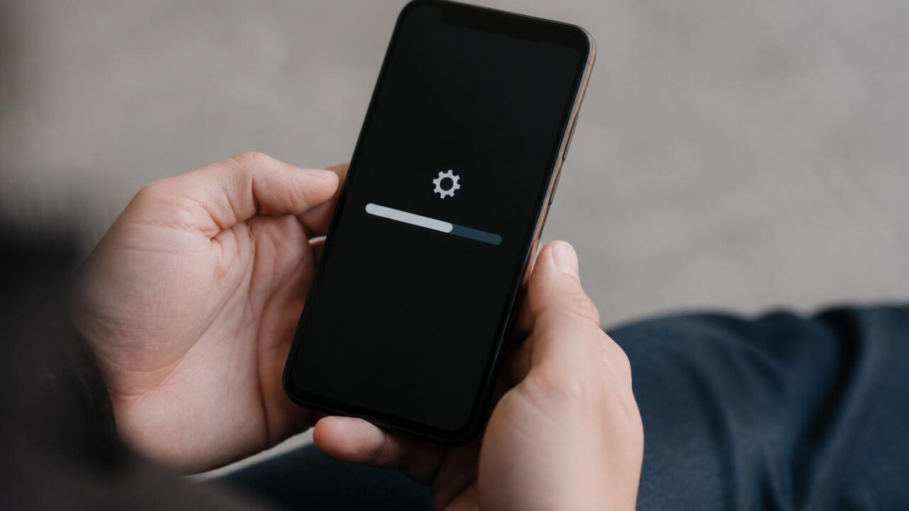 Pessoa segurando celular com tela de atualização travada